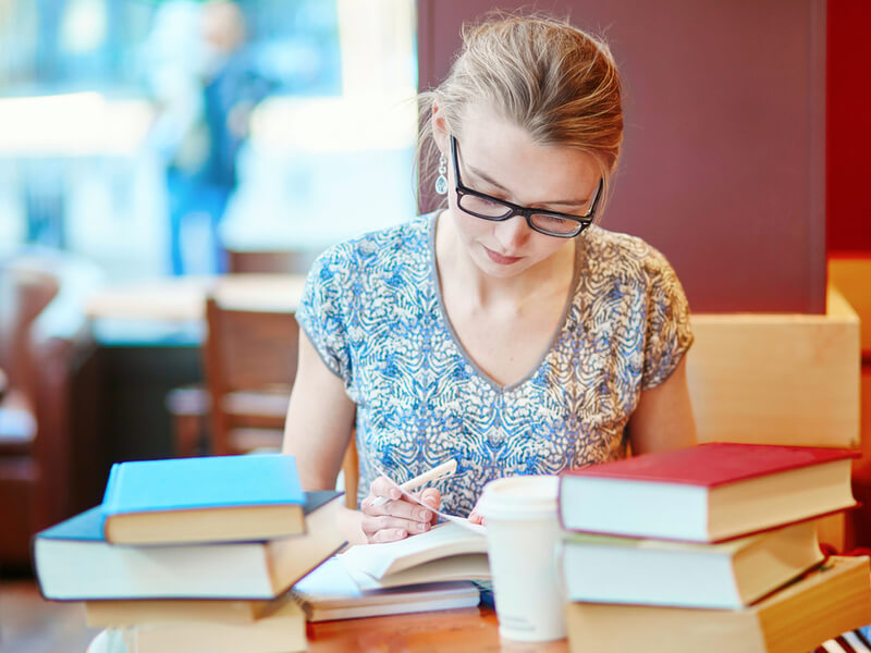 本に囲まれて勉強するメガネをかけた女性