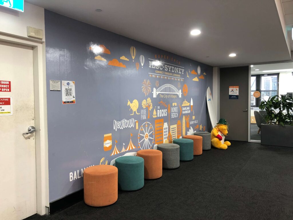 ILSC Sydneyの校内壁面アートとカラフルなスツールが並ぶ休憩スペース