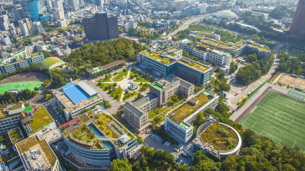 東国大学のキャンパス全景を捉えた航空写真、校舎やグラウンド、周囲の都市部が一望できる眺め