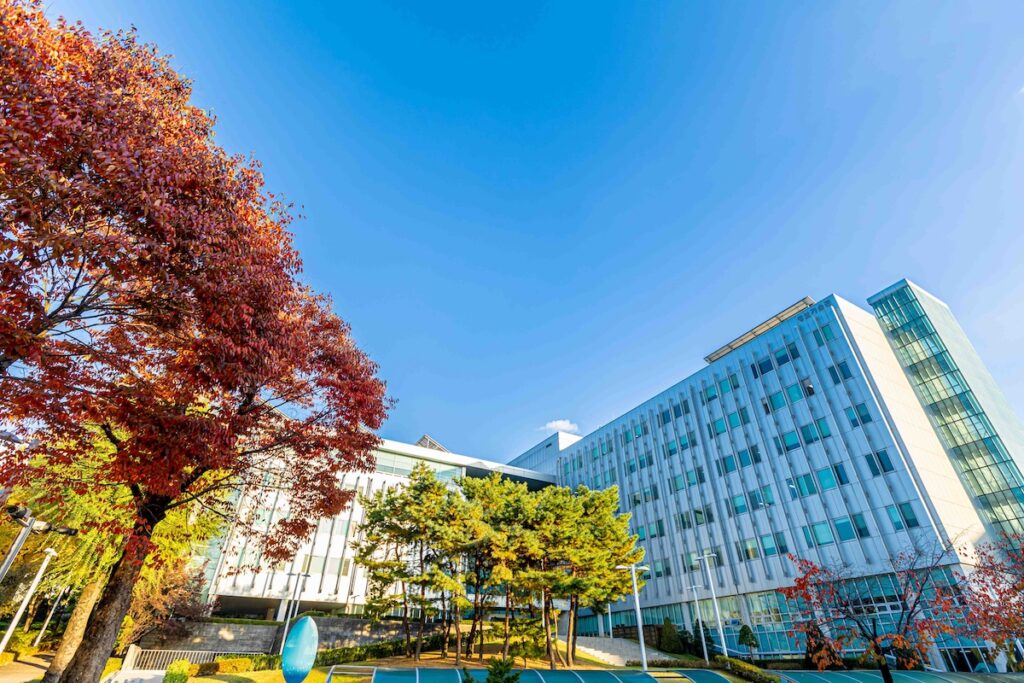 ソウル市立大学のキャンパス風景、秋の紅葉と現代的な校舎が青空の下に映える様子