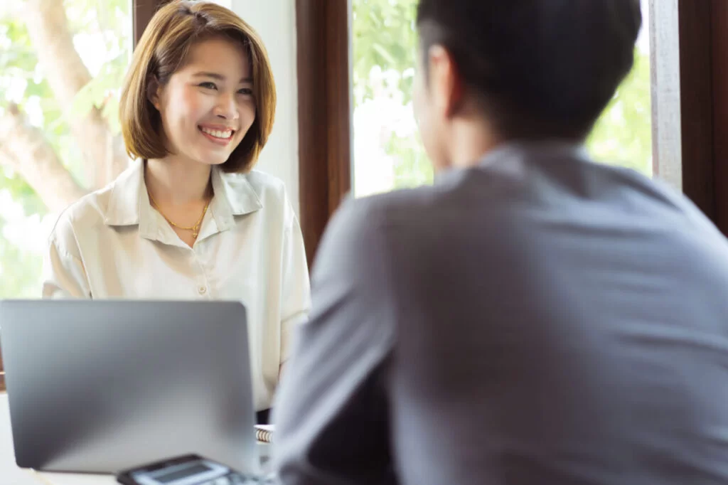 留学カウンセラーが学生と個別相談をしている様子(パソコンを使いながら笑顔でカウンセリング中)