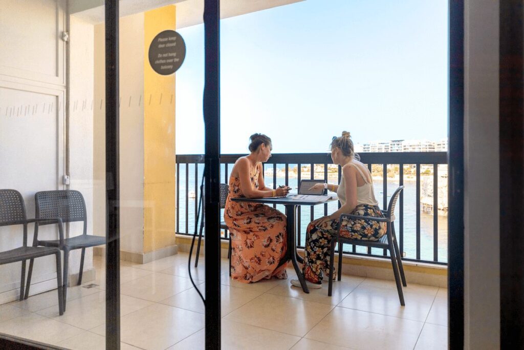 EFマルタ校で、海を望むバルコニーにて生徒同士がテーブルを囲み学習や会話をしている様子