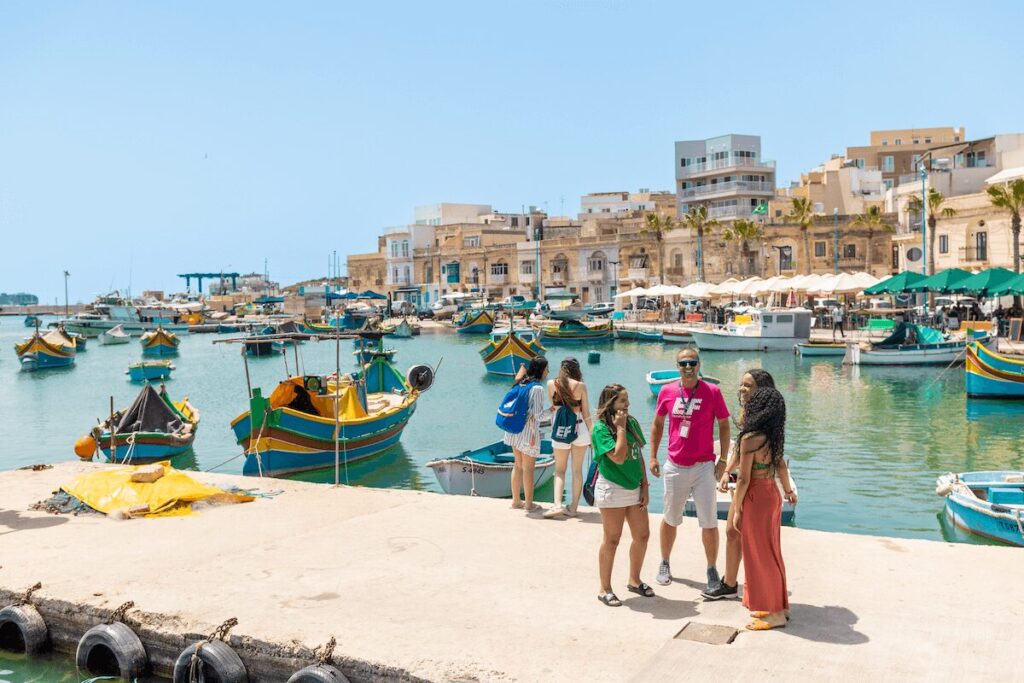 EFマルタ校のアクティビティで、マルタの港町を訪れた生徒とスタッフが海辺に集まっている様子