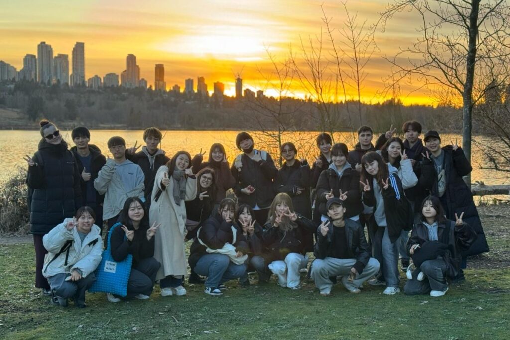 CESのバンクーバー・ジュニアプログラム参加者が、夕暮れの市街地を背景に撮影した集合写真