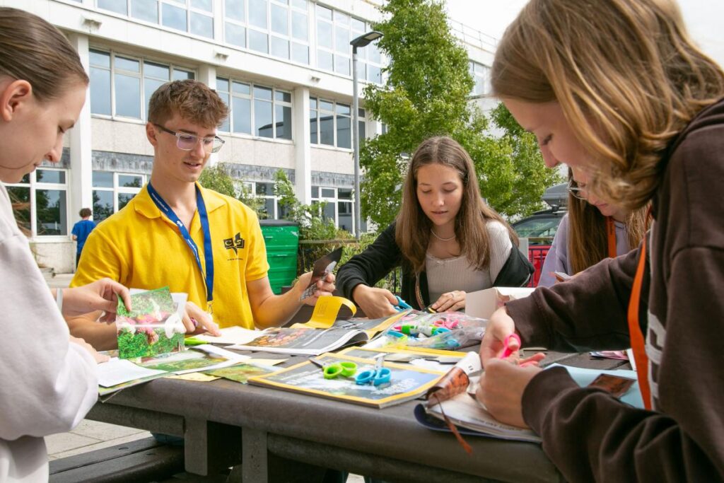 CESのカナダ・ジュニアプログラムで、屋外テーブルを囲みクラフト制作のアクティビティに取り組む参加者の様子