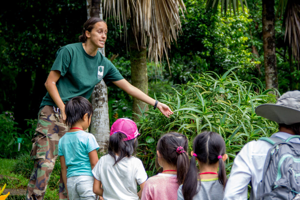 IIE HawaiiのKids & Teens Englishプログラムで、屋外の自然環境の中でインストラクターが子どもたちに説明している様子