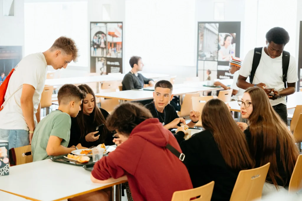 St Giles LondonのJunior Summerプログラムで、生徒たちが校内の共有スペースで食事や会話をしている様子