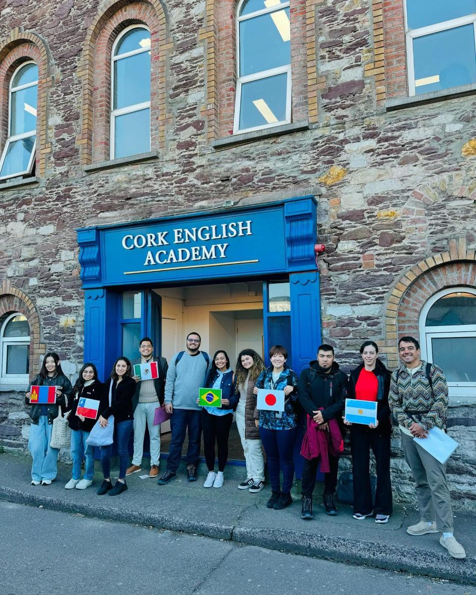 校舎前で各国の国旗を持つCork English Academyの学生たち
